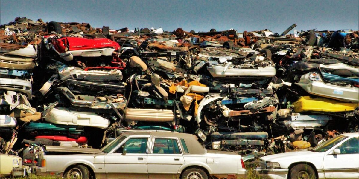 A large stack of disposed vehicles in an outdoor junkyard.